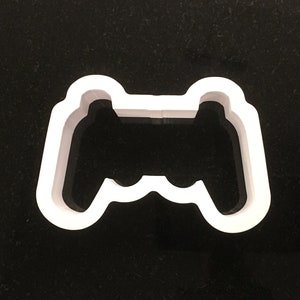 May include: White plastic cookie cutter shaped like a video game controller.
