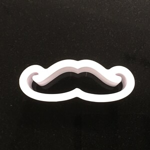 May include: White plastic cookie cutter shaped like a mustache.