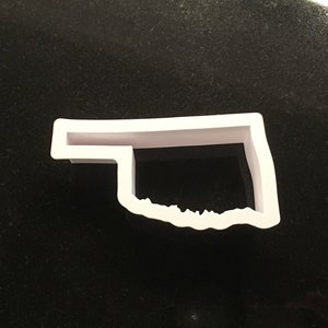 May include: White plastic cookie cutter shaped like the state of Oklahoma.
