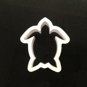May include: White plastic cookie cutter shaped like a turtle.