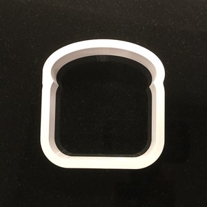 May include: White plastic cookie cutter shaped like a slice of bread.