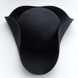 May include: A black felt tricorn hat with a wide brim and a rounded crown.