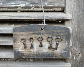 Ancienne planche en bois vintage maintenant comme petit porte-clés avec 5 clés anciennes à patine minable