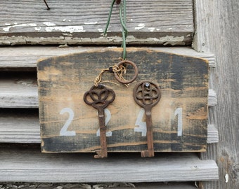 Ancienne planche en bois vintage maintenant comme petit porte-clés avec 2 clés anciennes à patine minable