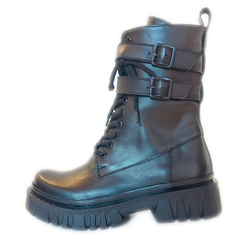 K&ouml;nnte beinhalten: Schwarzer Leder-Combat-Stiefel mit klobiger Sohle. Der Stiefel hat zwei Schnallenriemen um den Kn&ouml;chel und einen Schn&uuml;rverschluss. Am oberen Teil des Stiefels befindet sich eine Zuglasche. Der Stiefel hat eine Profilsohle.