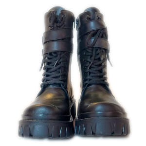 K&ouml;nnte beinhalten: Ein Paar schwarze Kampfstiefel mit dicken Sohlen. Die Stiefel haben Schn&uuml;rsenkel, Riemen mit Schnallen und einen seitlichen Rei&szlig;verschluss. Sie bestehen aus einem gl&auml;nzenden, lederartigen Material, vor wei&szlig;em Hintergrund.