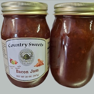 May include: Two glass jars of Country Sweets Bacon Jam, each with a gold lid and a label that reads "Country Sweets", "bee kind", "Bacon Jam", and "NET WT 20 OZ. (567g)".