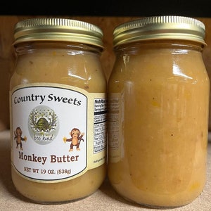 May include: Two glass jars of Monkey Butter, a honey-based spread, with gold lids. The jars are labeled "Country Sweets" and "bee kind". The jars are 19 ounces (538 grams) each.