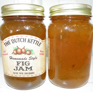 Peut inclure: Deux pots en verre de confiture de figues faite maison, étiquetés "The Dutch Kettle Homemade Style Fig Jam", avec un poids net de 19 oz (538 grammes). Les pots ont des couvercles dorés et sont remplis d'une confiture de couleur ambre clair.