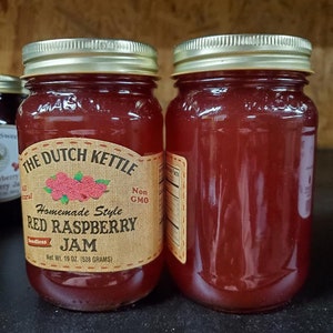 May include: Two glass jars of red raspberry jam labeled "The Dutch Kettle Homemade Style Red Raspberry Seedless Jam" with a net weight of 19 oz (538 grams).