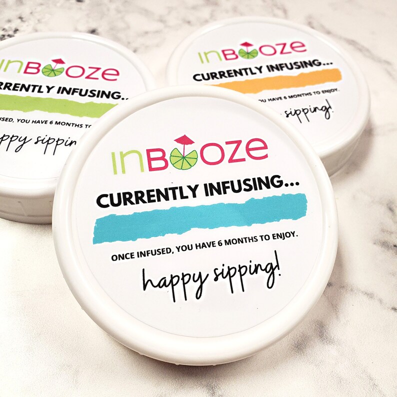 Puede incluir: Tres recipientes redondos blancos con tapas. Cada tapa tiene una etiqueta colorida con el texto "inBooze" y la frase "Currently Infusing..."  Las etiquetas tambi&eacute;n incluyen una lima y un paraguas de playa. Una etiqueta tiene el texto "Una vez infundido, tienes 6 meses para disfrutarlo. &iexcl;Feliz degustaci&oacute;n!"