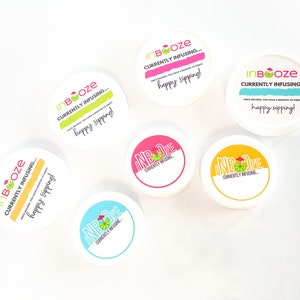 Puede incluir: Seis recipientes redondos blancos con etiquetas de colores que dicen "InBooze" y "Currently Infusing... happy sipping!"