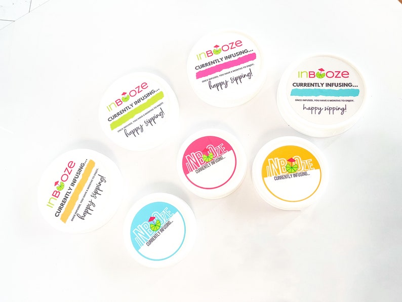 Puede incluir: Seis recipientes redondos blancos con etiquetas de colores que dicen "InBooze" y "Currently Infusing... happy sipping!"