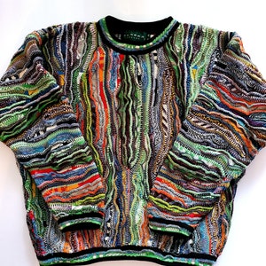 May include: Multicolored knit sweater with a unique, abstract pattern. The sweater has a crew neck and long sleeves. The brand name "Sudora" is visible on the tag.