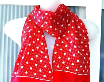 Peut inclure: Écharpe à pois rouge et blanc avec une bordure blanche. L'écharpe est pliée en deux et drapé sur un mannequin blanc.
