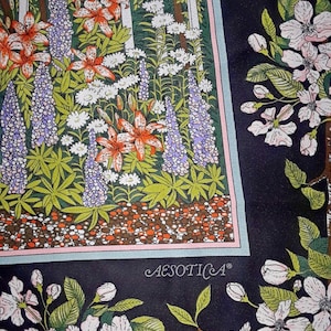 May include: A black and white floral print fabric with a white picket fence and a garden scene. The fabric features a variety of flowers, including lilies, lupines, and daisies. The fabric also features a small, white text label that reads "AESOTICA".
