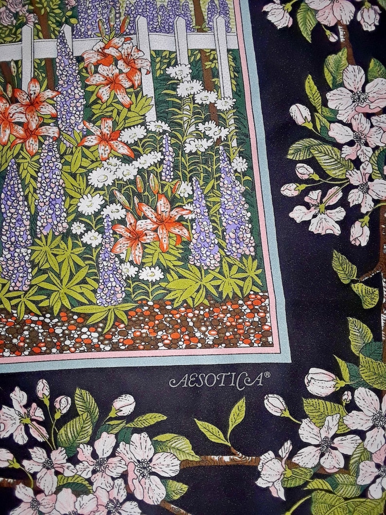 May include: A black and white floral print fabric with a white picket fence and a garden scene. The fabric features a variety of flowers, including lilies, lupines, and daisies. The fabric also features a small, white text label that reads "AESOTICA".