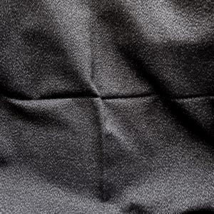 May include: Close-up of a dark gray fabric with a subtle sheen. The material has a textured surface with visible folds and creases, creating shadows and highlights. The fabric appears to be tightly woven.