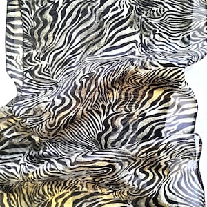 May include: A sheer scarf with a black and white zebra stripe pattern. The fabric is draped, showing the flowing nature of the material. The scarf has a light, airy appearance.