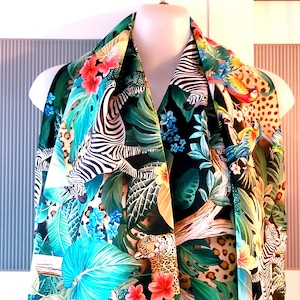 May include: A colourful silk scarf with a jungle print featuring zebras, parrots, leopards, and tropical plants on a black background.