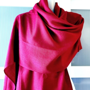 May include: A deep crimson red knitted scarf draped over a mannequin. The scarf is soft and flowing, with a subtle texture.