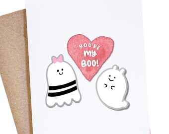 May include: A white card with a pink heart that says "You're my Boo!" and two white ghost illustrations. One ghost has black stripes and a pink bow. The other ghost has a small smile.