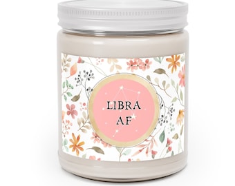 Könnte beinhalten: Ein weißes Kerzengefäß mit einem rosa und goldenen Etikett, auf dem "LIBRA AF" mit einem Blumenmuster steht. Das Etikett hat einen rosa Kreis mit einem Sternbildmuster.