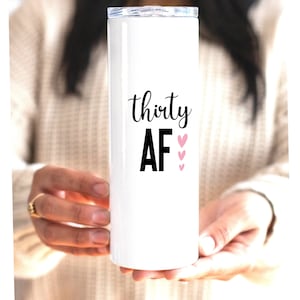 May include: White stainless steel tumbler with a black inscription that reads "thirty AF" and pink hearts.