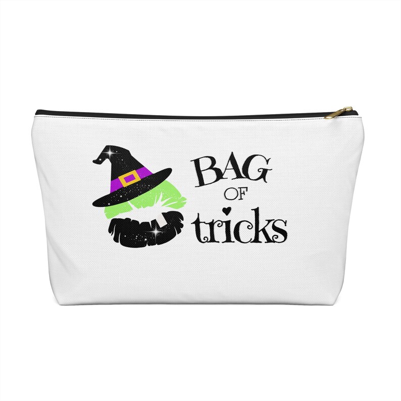 May include: White zippered pouch with a black zipper and a black and green witch's hat with a purple band and a gold buckle. The text "BAG OF tricks" is printed in black below the hat.