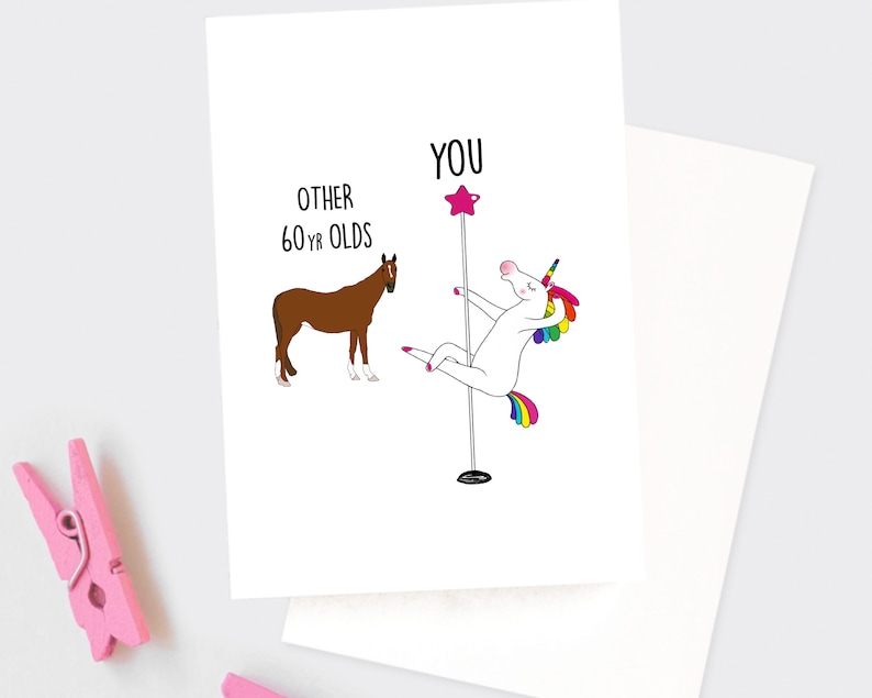 May include: A greeting card with a white unicorn holding a pole and a brown horse. The text on the card reads "You" above the unicorn and "Other 60-yr olds" above the horse.