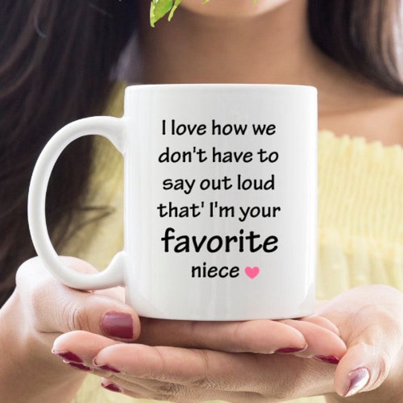 May include: White ceramic mug with black text that reads "I love how we don't have to say out loud that I'm your favorite niece" with a pink heart.