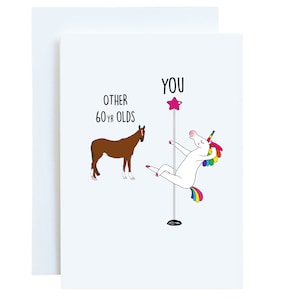 May include: A greeting card with a white unicorn holding a pink star on a pole. The unicorn has a rainbow mane and tail. The text on the card reads "YOU" above the unicorn and "OTHER 60 YR OLDS" next to a brown horse.