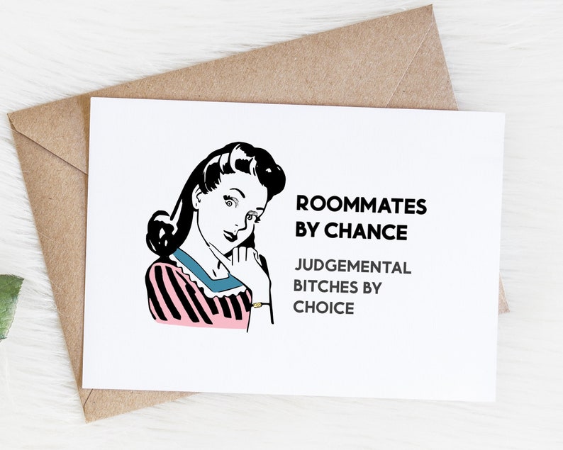 May include: A white card with a black and white illustration of a woman with a pink and black striped shirt. The text on the card reads "Roommates by chance, Judgemental Bitches by choice."