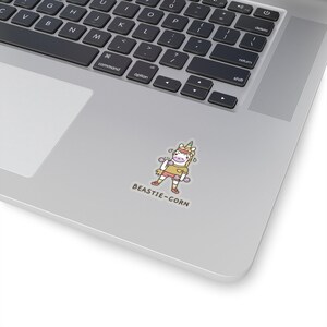 May include: A sticker featuring a cartoon unicorn with a rainbow horn, wearing a pink shirt and holding pink dumbbells. The unicorn is sweating and has a happy expression. The text "BEASTIE-CORN" is below the unicorn.