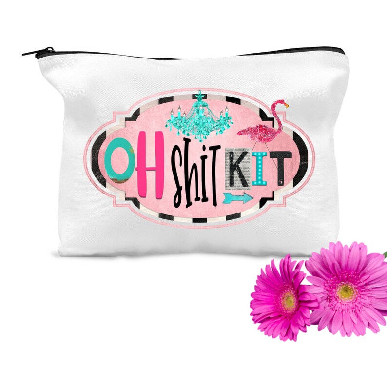 K&ouml;nnte beinhalten: Wei&szlig;e Canvas-Kosmetiktasche mit einem rosafarbenen ovalen Design, das den Text "OH SHIT KIT" in schwarzer und rosa Schrift zeigt. Ein t&uuml;rkisfarbener Kronleuchter und ein rosa Flamingo sind ebenfalls im Design enthalten.