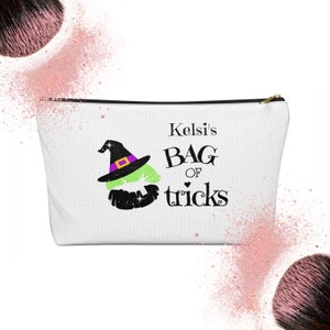 May include: White zippered makeup bag with a green witch with a purple hat and the text "Kelsi's Bag of tricks".