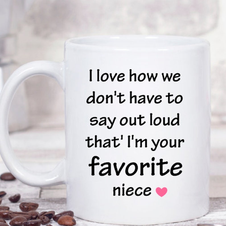 May include: White ceramic coffee mug with a black inscription that reads "I love how we don't have to say out loud that I'm your favorite niece".
