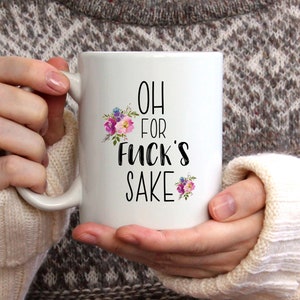 K&ouml;nnte beinhalten: Eine wei&szlig;e Keramiktasse mit einem schwarzen Blumendesign und dem Text "OH FOR FUCK'S SAKE".