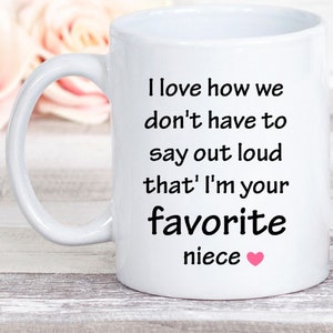 May include: White ceramic mug with a black inscription that reads "I love how we don't have to say out loud that I'm your favorite niece" with a pink heart.
