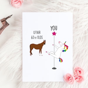 May include: A humorous birthday card featuring a unicorn on a pole dancing, with the text "You" above it.  The text "Other 60 yr olds" is above a brown horse.