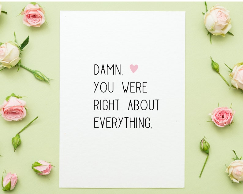 Puede incluir: Una tarjeta blanca con el texto "DAMN. YOU WERE RIGHT ABOUT EVERYTHING." y un s&iacute;mbolo de coraz&oacute;n rosa. La tarjeta est&aacute; rodeada de rosas rosas y capullos sobre un fondo verde claro.
