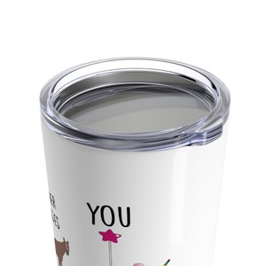 Pu&ograve; includere: Un bicchiere in acciaio inossidabile bianco con un coperchio. Il bicchiere ha una grafica in bianco e nero che dice "You are my sunshine" con un unicorno arcobaleno, un cuore rosa e una mucca marrone.