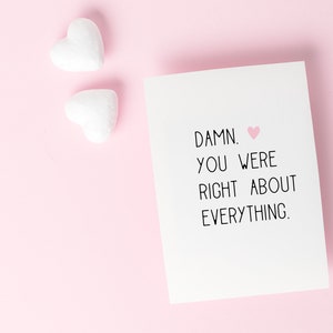 Puede incluir: Una tarjeta blanca con un coraz&oacute;n rosa y el texto "DAMN. YOU WERE RIGHT ABOUT EVERYTHING."