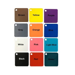 May include: Twelve square colour swatches are displayed, each with a small hole in the upper left corner. The swatches showcase a range of colours: brown, yellow, purple, grey, orange, blue, white, pink, light blue, black, red, and green.
