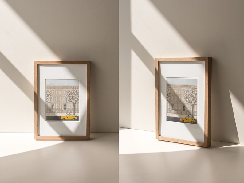 May include: Two framed illustrations of a city street scene with a yellow taxi cab in front of a brownstone building. The frames are made of natural wood and have a white mat.