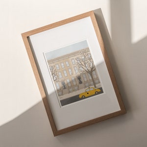 May include: A framed illustration of a yellow taxi cab parked in front of a row of brownstone buildings with trees in the foreground.