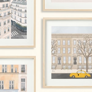 May include: A set of three framed illustrations of cityscapes. The first image shows a view of a Parisian street with buildings in the background. The second image shows a view of a New York City street with a yellow taxi cab in the foreground. The third image shows a view of a Parisian street with buildings in the background.