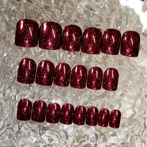 May include: Set of 20 burgundy glitter press-on nails. The nails are short and oval shaped.