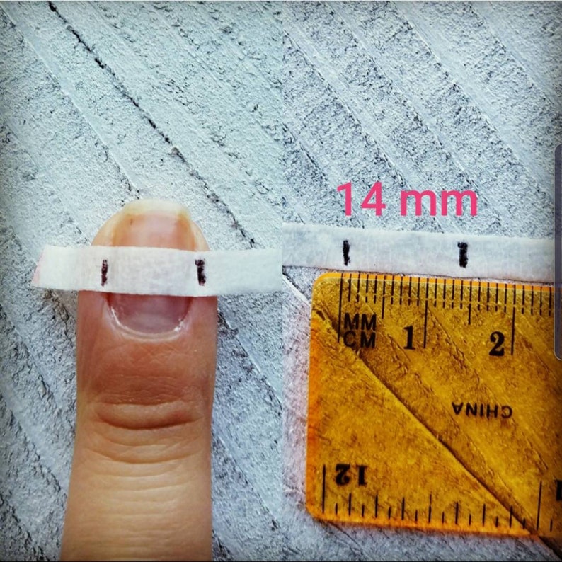 May include: A close-up of a finger with a white measuring tape wrapped around it. A yellow ruler is placed next to the finger, showing a measurement of 14 mm. The text "14 mm" is written in pink.