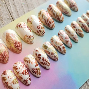 White nails with golden brown leaves, fake nails, press on nails, fall nails. Fall leaves, brown leaves. Choice of matte or glossy finish.